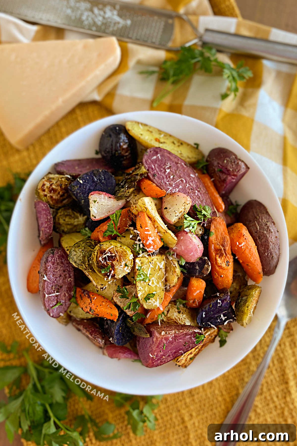 Bowl of perfectly roasted root vegetables topped with Parmesan cheese, ready for serving on a festive table.