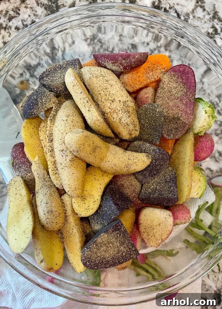 Sliced root vegetables in a mixing bowl, glistening with olive oil and a blend of seasonings, ready to be tossed.