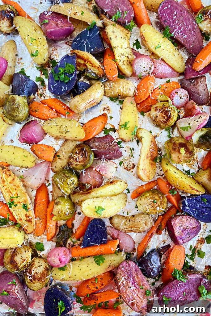 Close-up of roasted carrots, fingerling potatoes, radishes, and Brussels sprouts, golden and tender, on a sheet pan.