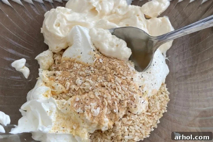 Ultimate Creamy Baked Spinach Artichoke Dip 3 Mixing mayonnaise, sour cream, and various seasonings in a large bowl to create the dip base.