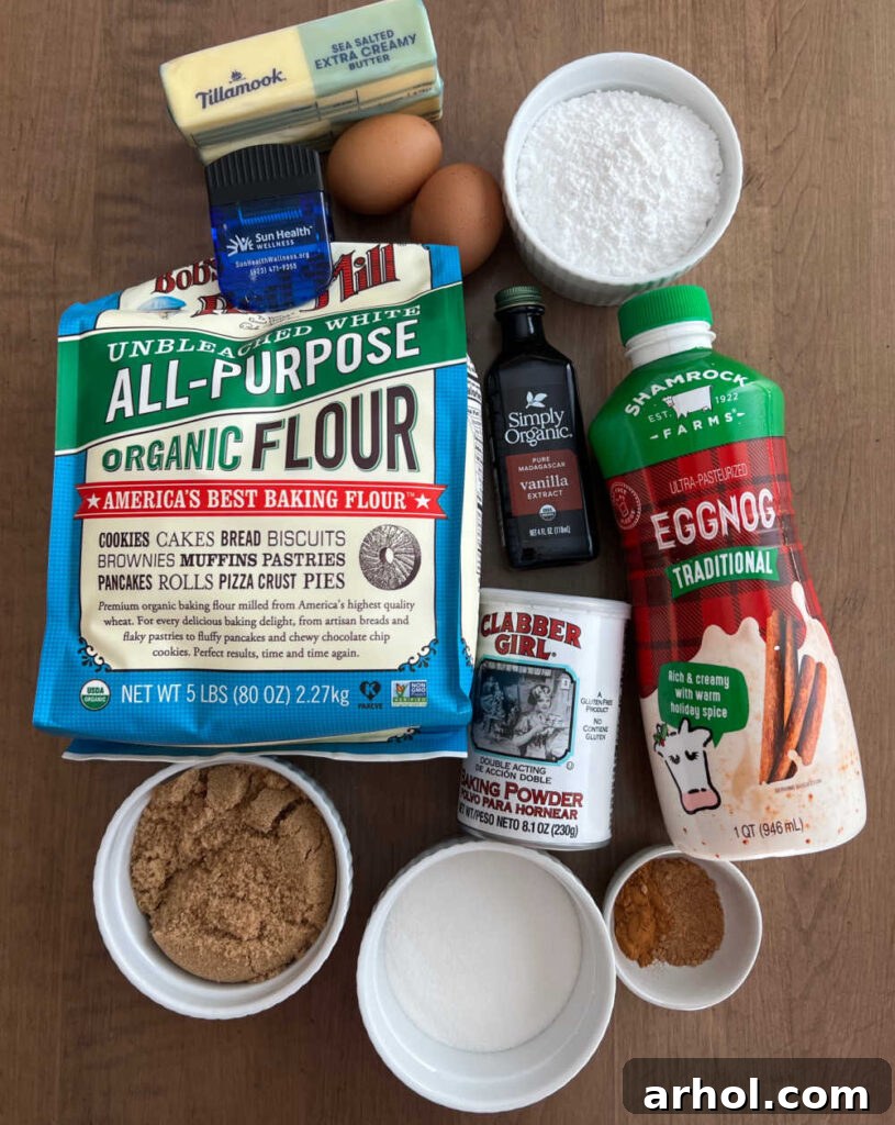 Melt In Your Mouth Glazed Eggnog Cookies 3 A beautiful flat lay photograph showcasing all the essential ingredients for eggnog cookies, including flour, eggs, butter, baking powder, vanilla extract, rich eggnog, brown sugar, granulated sugar, warm spices like cinnamon and nutmeg, and powdered sugar for the glaze.
