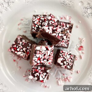 chocolate peppermint fudge with crushed candy canes on top on a white plate, ready to be served