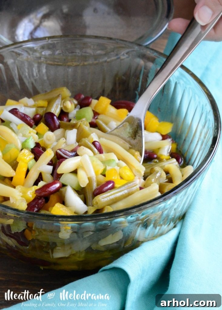 A large mixing bowl prominently displaying the perfectly combined three bean salad ingredients, thoroughly coated with the delicious dressing, showcasing a medley of vibrant colors and appealing textures.