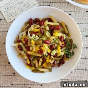 three bean salad in a white serving bowl with original recipe card.