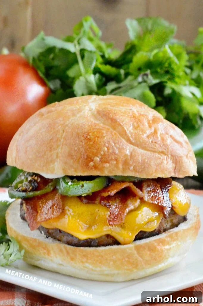 cheeseburger topped with bacon slices and jalapeno peppers on a plate
