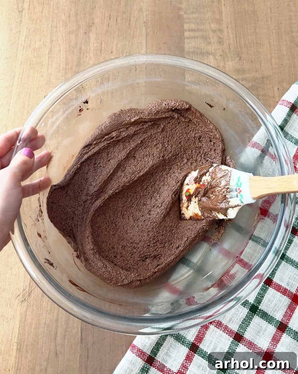 A large bowl shows melted chocolate, cocoa, fluff, and butter being mixed together.