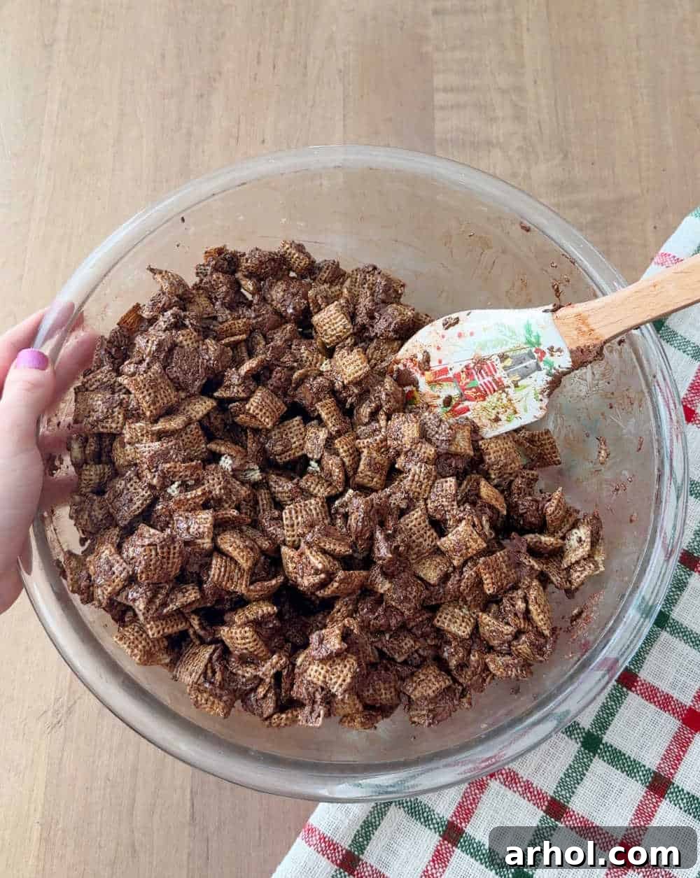 Rice Chex cereal is being stirred into the chocolate mixture in a bowl.