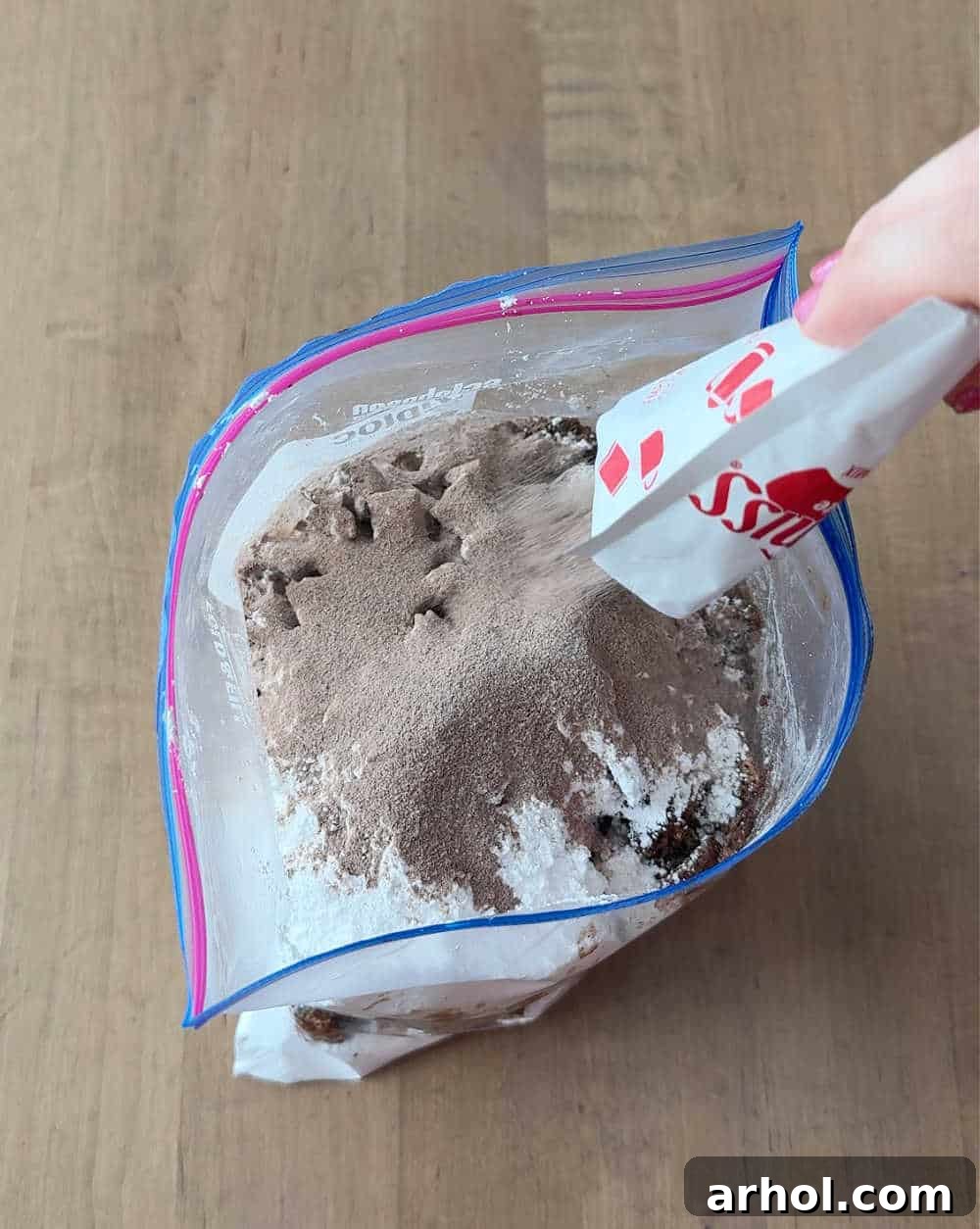 Hot chocolate mix is being added to a large ziplock bag filled with cereal.