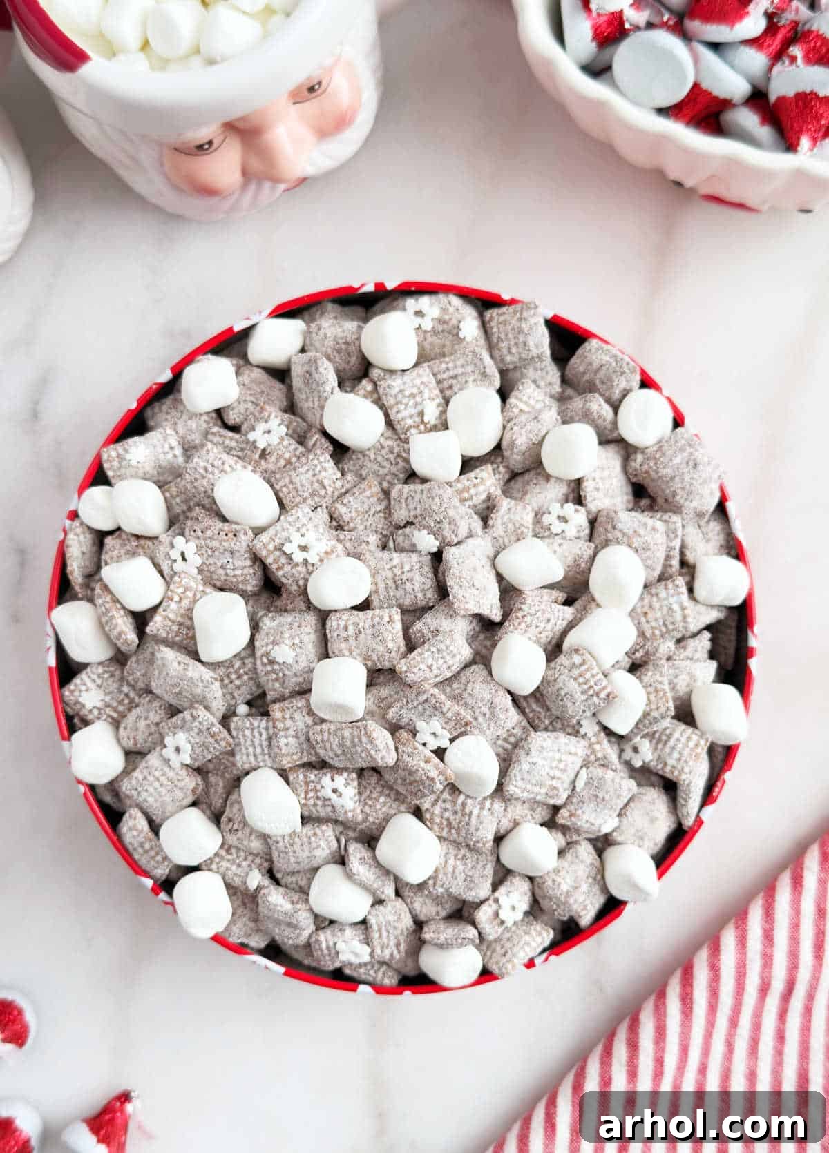 A festive red tin is filled to the brim with Hot Cocoa Puppy Chow, ready for sharing or enjoying.