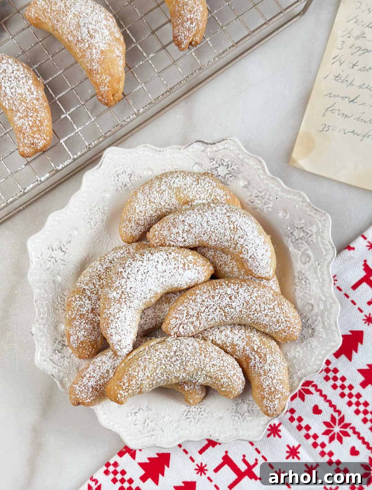 Slovak Polish nut horns elegantly arranged on a pristine white plate, showcasing their perfect crescent shape and snowy powdered sugar topping.