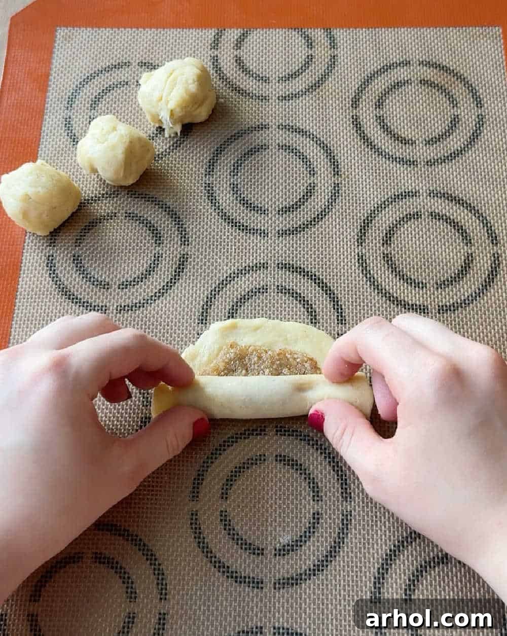 Hands rolling up the filled cookie dough to form a log shape.
