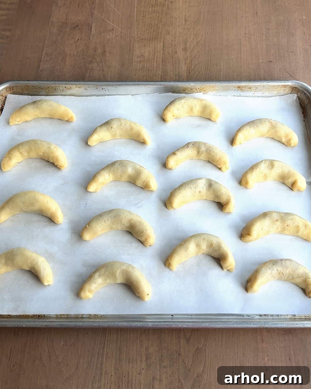 Perfectly shaped nut horn crescents arranged on a baking sheet, ready for the oven.
