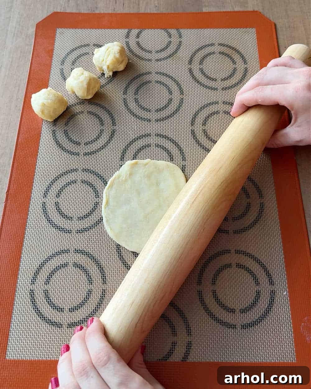 Rolling out small circles of cookie dough on a floured surface.