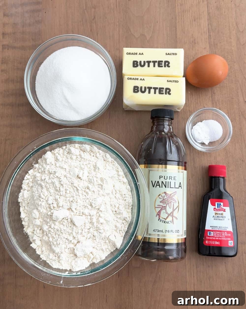 Essential ingredients for baking delicious sugar cookies: flour, sugar, butter, egg, vanilla, almond extract, baking soda, salt.