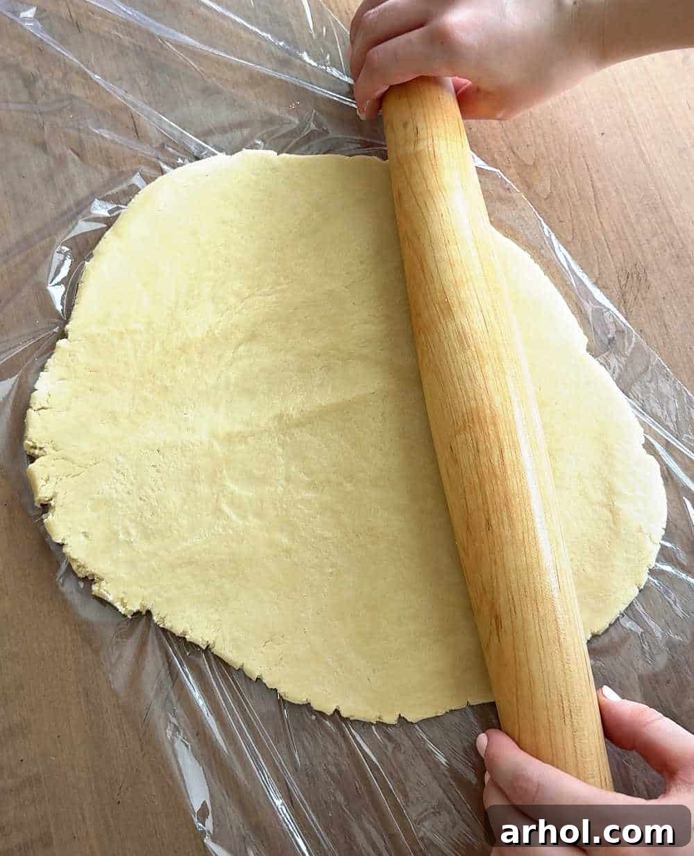 Rolling dough out on plastic wrap.