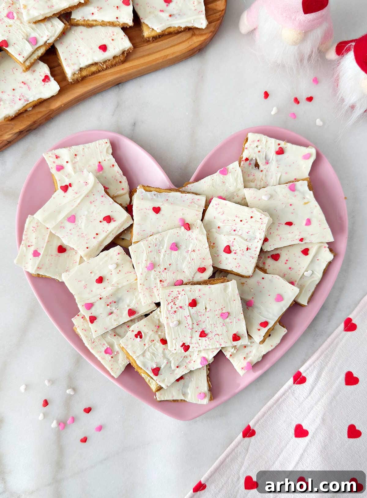 White chocolate Valentines crack candy on heart shaped plate, beautifully adorned with pink and red sprinkles, ready to be enjoyed or gifted.