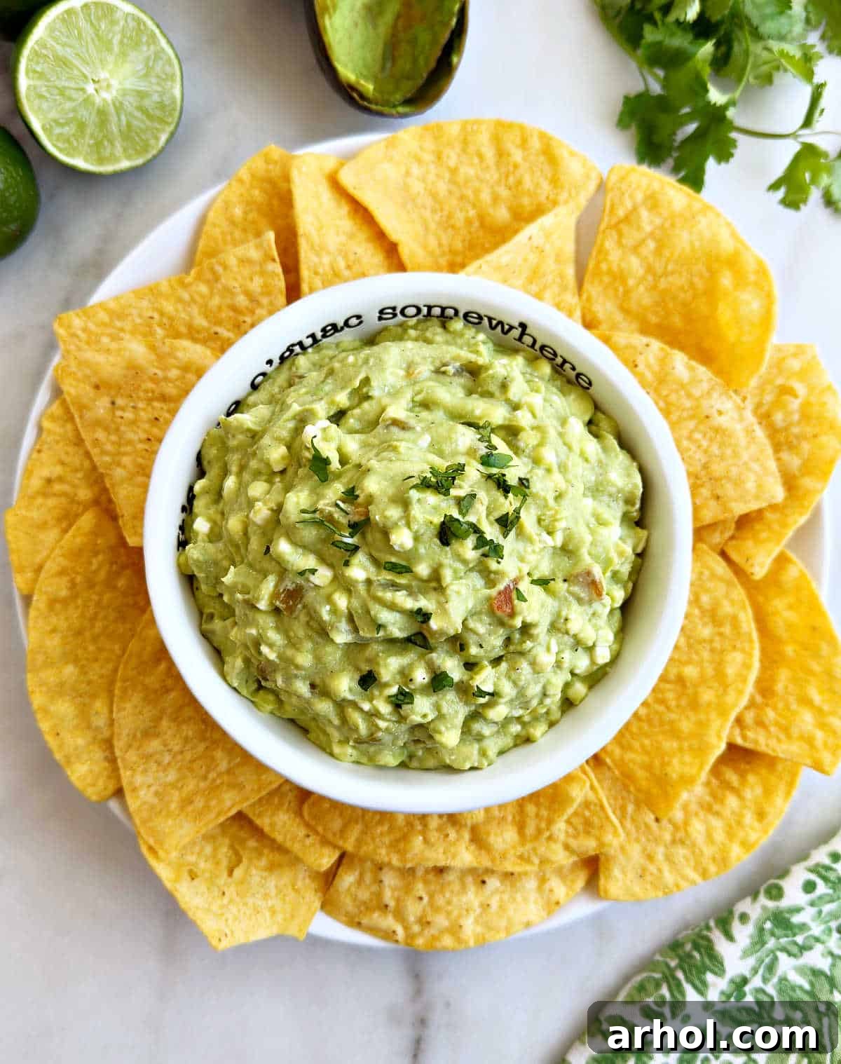 Bowl of avocado dip with cottage cheese, garnished with fresh cilantro and served with a variety of tortilla chips.