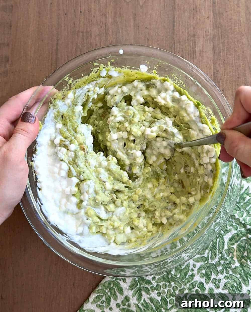 Stirring cottage cheese into the avocado and spice mixture, creating a creamy texture.