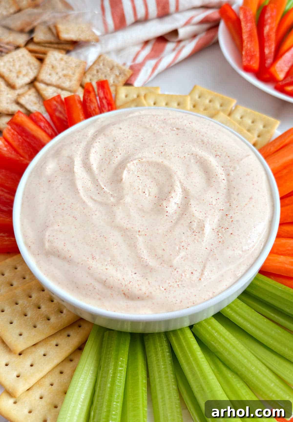A vibrant bowl of ghost pepper dip, surrounded by an assortment of fresh, colorful vegetables and crunchy crackers, ready for dipping and enjoying.