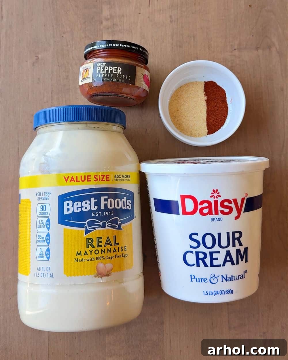 Four small bowls containing the individual ingredients for the ghost pepper dip: mayonnaise, sour cream, ghost pepper puree, and a blend of spices.