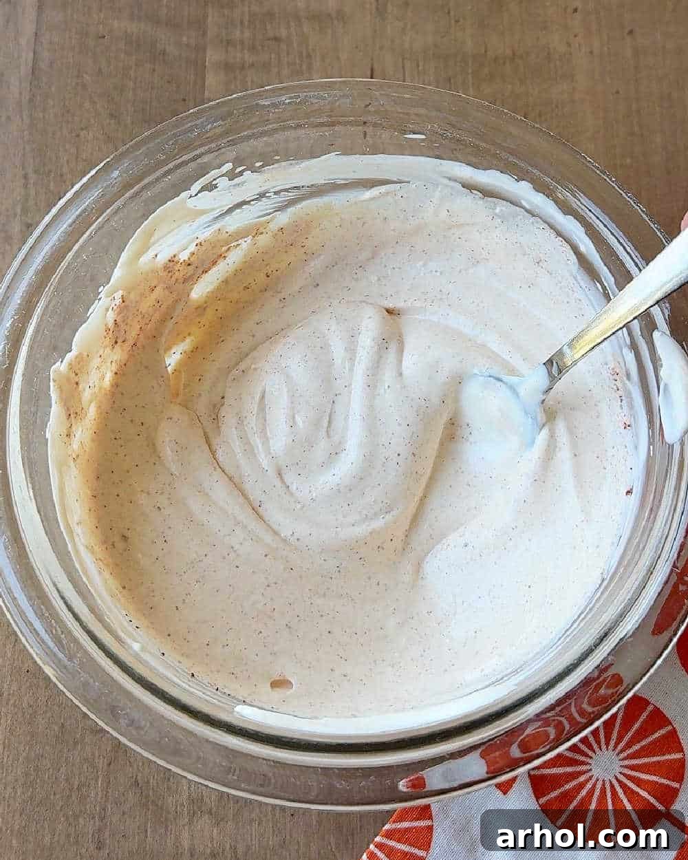 A close-up shot of the ghost pepper dip being thoroughly stirred in a small bowl with a spoon, achieving a uniform, creamy texture and consistent color.