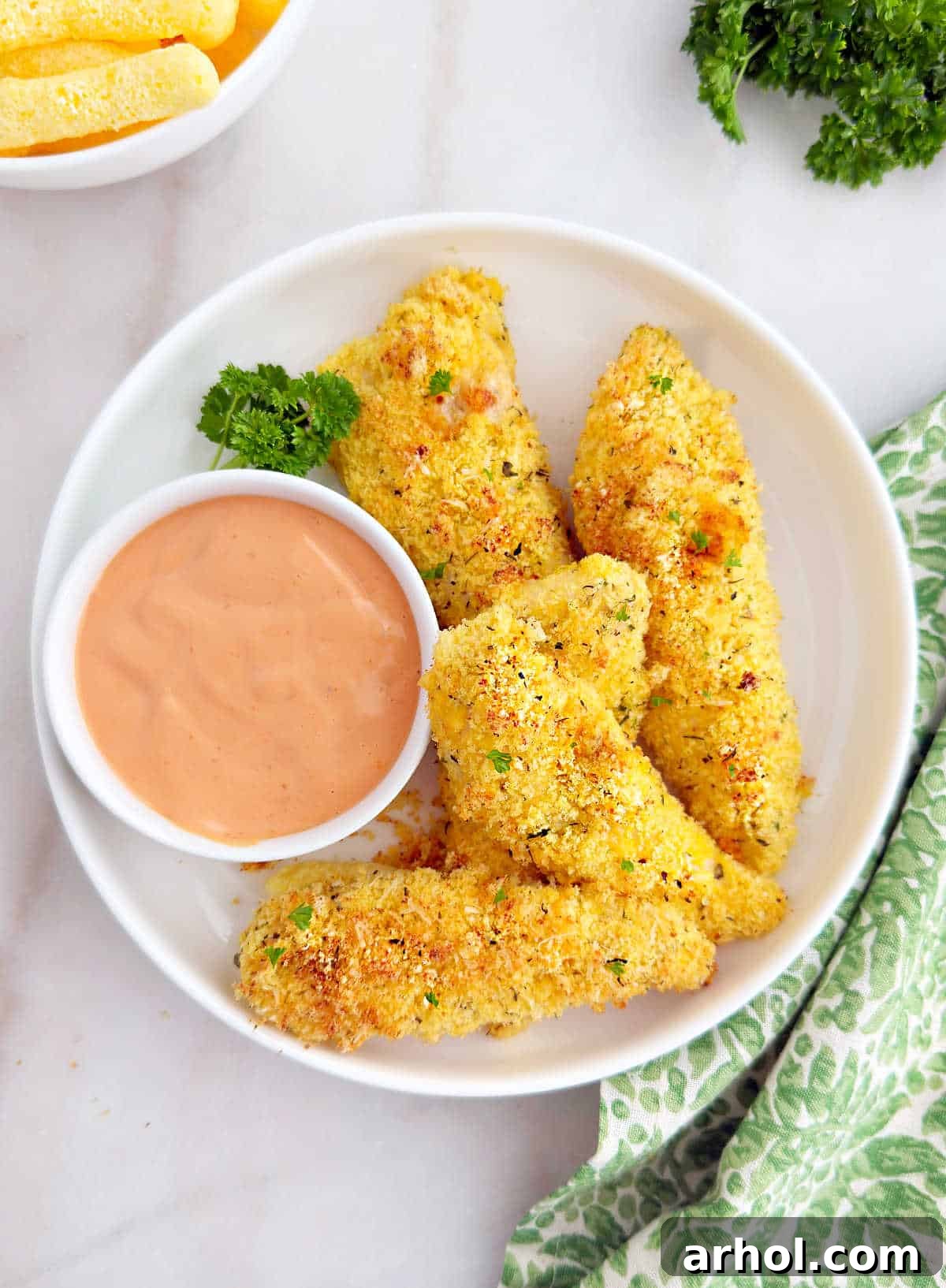Plate of crispy white cheddar Cheetos chicken tenders with a side of creamy dipping sauce.