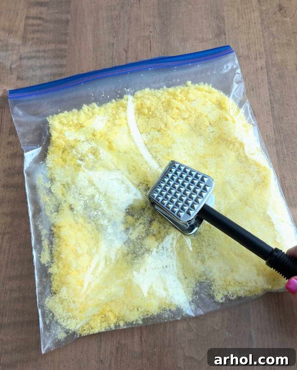 Crushing Cheetos puffs using a meat mallet in a zip-top bag.