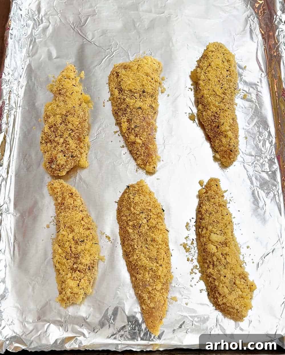 Crispy breaded chicken strips arranged on a baking sheet, ready for the oven.