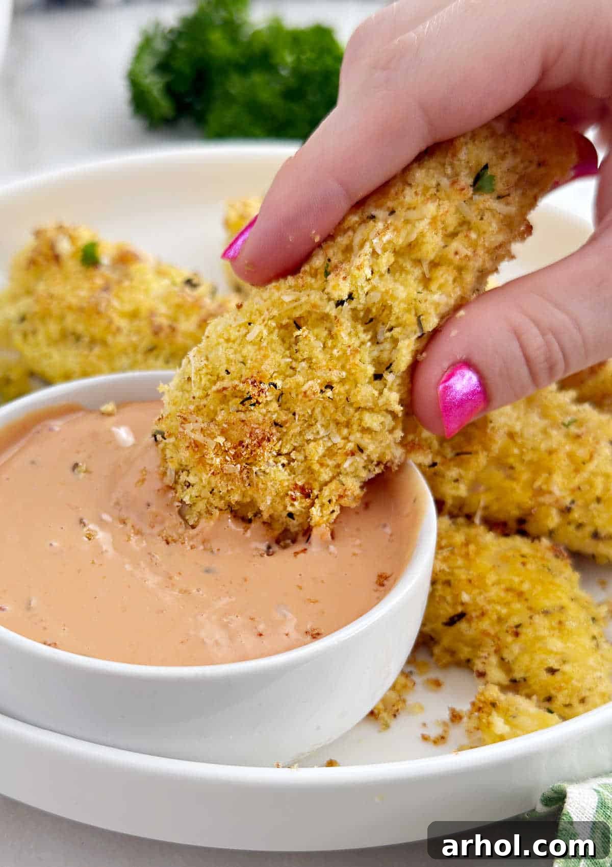 Dunking a crispy Cheetos chicken tender into a creamy white dipping sauce.