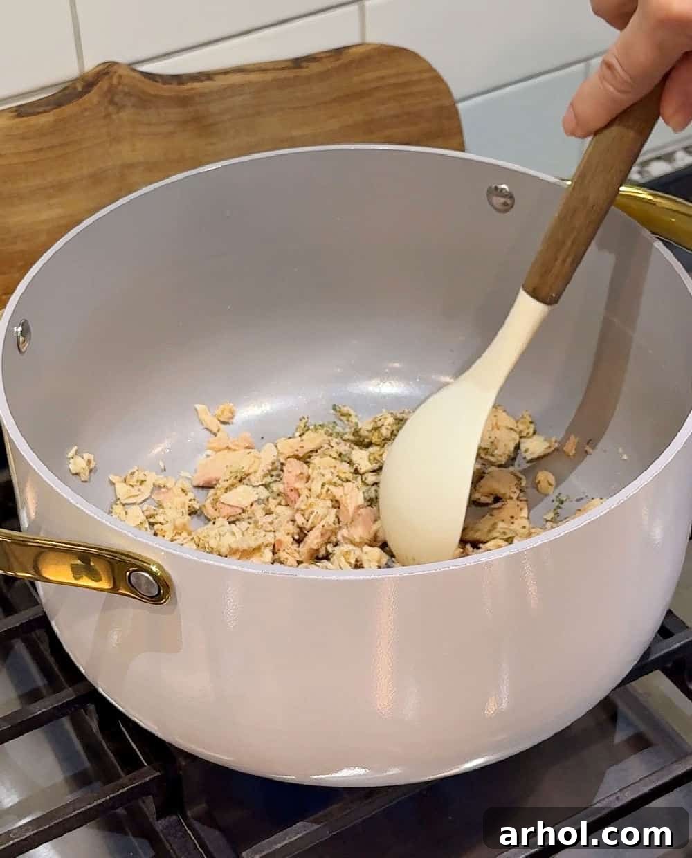 Canned tuna being stirred in a pot with dried seasonings.