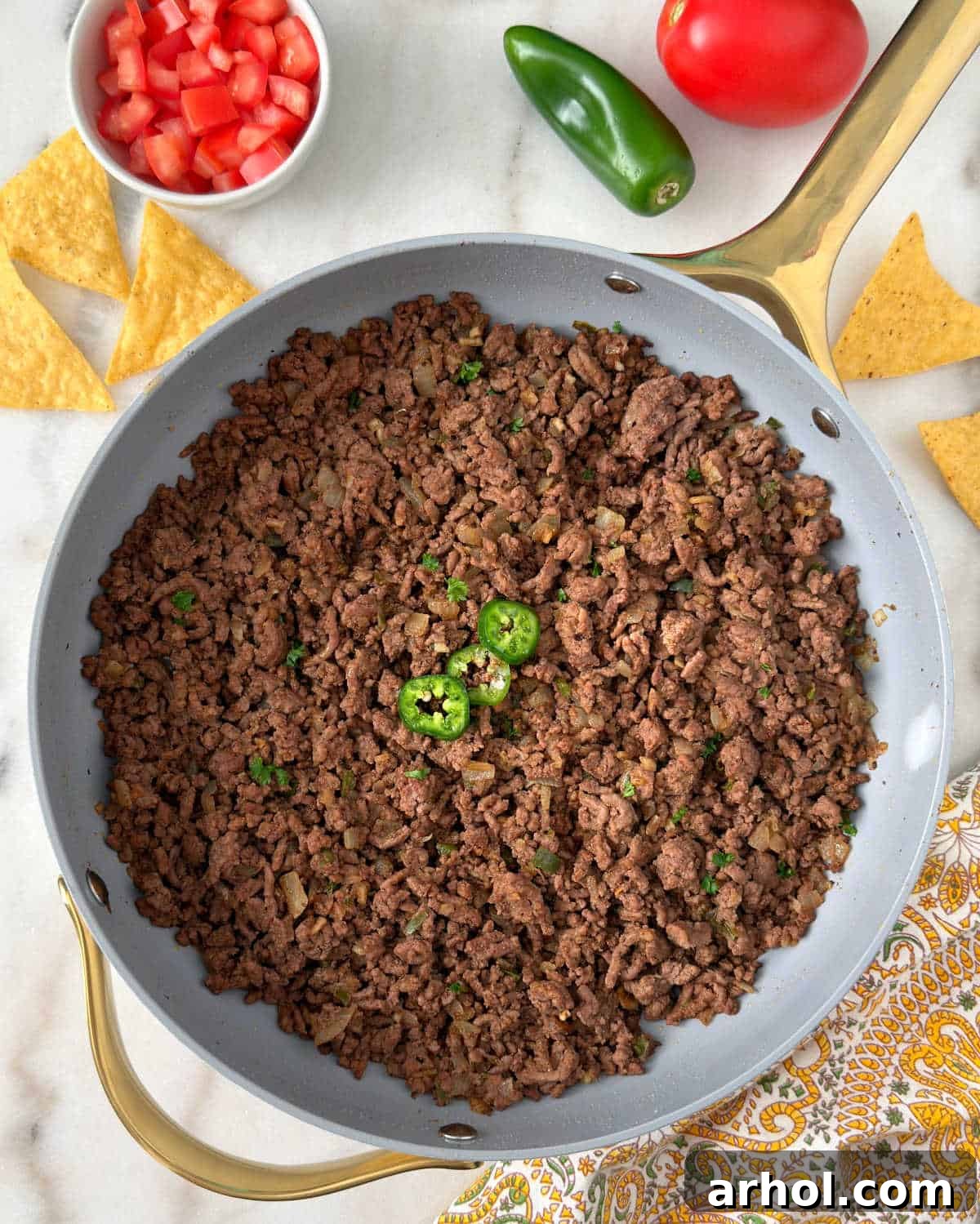 Sizzling ground beef taco meat in a skillet, garnished with fresh jalapeño slices, ready to be served.