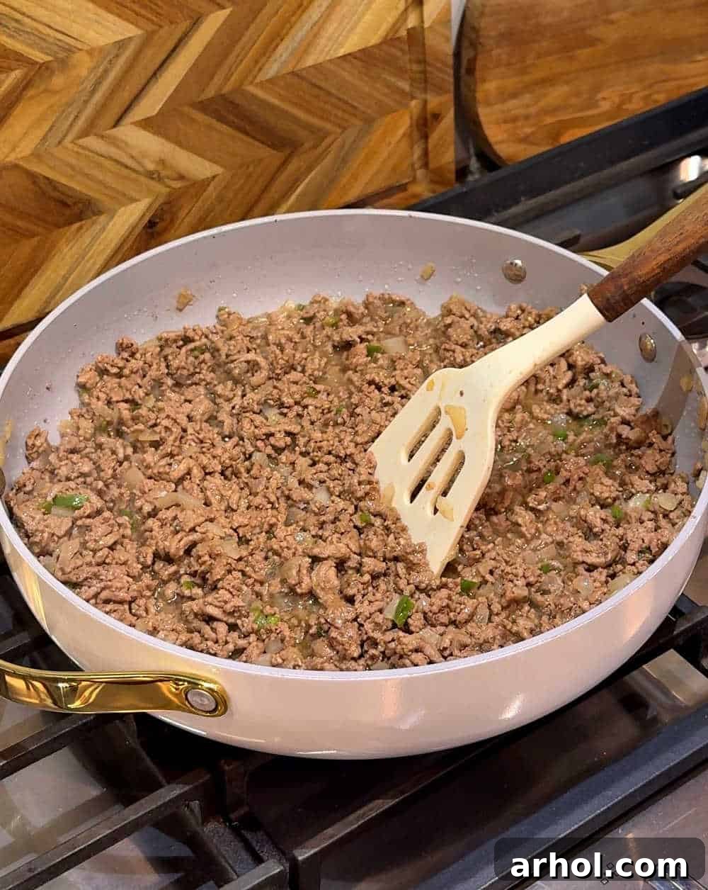 Browning lean ground beef in a skillet, crumbling it with a spatula until no pink remains.