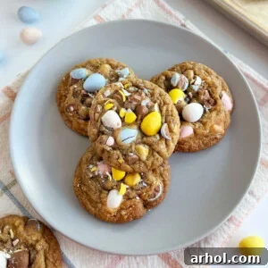 Irresistible Cadbury Mini Egg Cookies, generously studded with colorful mini chocolate candy eggs, presented on a cheerful blue plate.