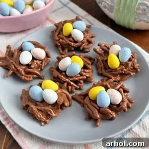Adorable birds nest cookies crafted with chocolate-coated chow mein noodles and decorated with colorful candy eggs, creating a playful and festive Easter treat.