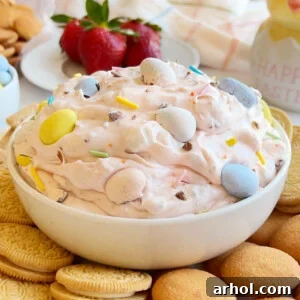 A creamy Cadbury Mini Eggs Cheesecake Dip served in a pristine white bowl, surrounded by various dippers such as graham crackers and vanilla wafers.