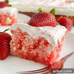 A delectable Strawberry Jello Poke Cake topped with a generous layer of Cool Whip and adorned with fresh, juicy strawberries, making a vibrant and irresistible dessert.