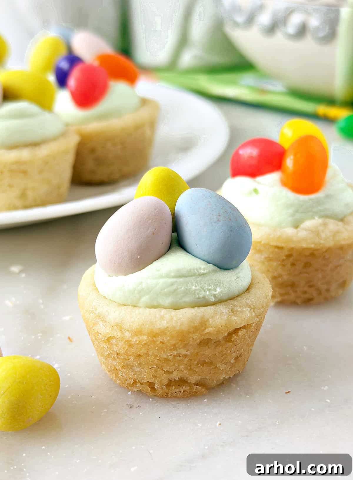 Adorable Easter Cookie Basket Nests 2 Festive Easter basket cookie cups overflowing with colorful candy eggs and green frosting, ready to be enjoyed.