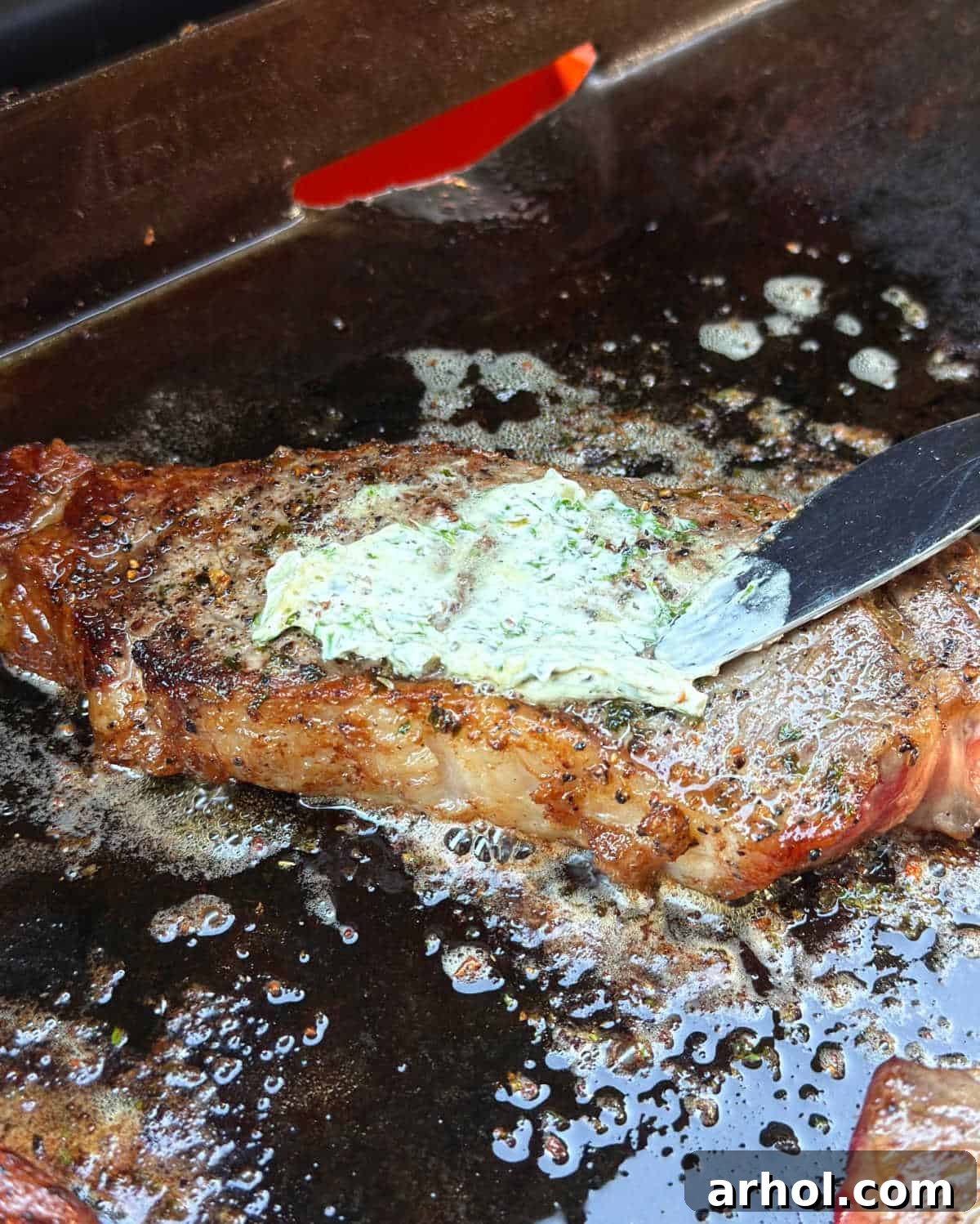 spreading herb butter on steak.