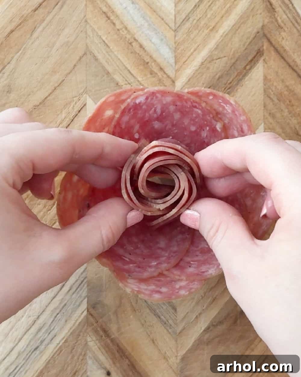 Step 7: Gently inserting the rolled salami core into the center of the glass, completing the salami rose formation before placing it on the board.
