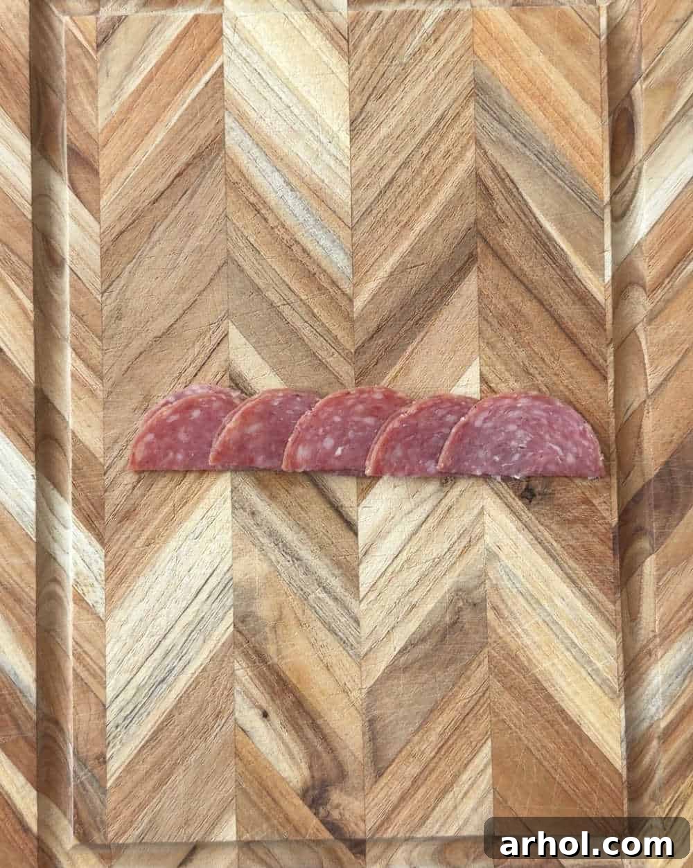 Step 4: Folding salami slices in half and lining them up on a cutting board, ready to be rolled into the center of a rose.
