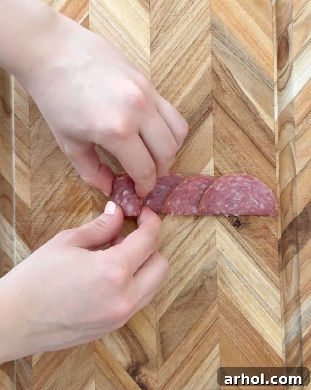 Step 5: Carefully rolling the folded salami slices together to create a compact core for the salami rose.