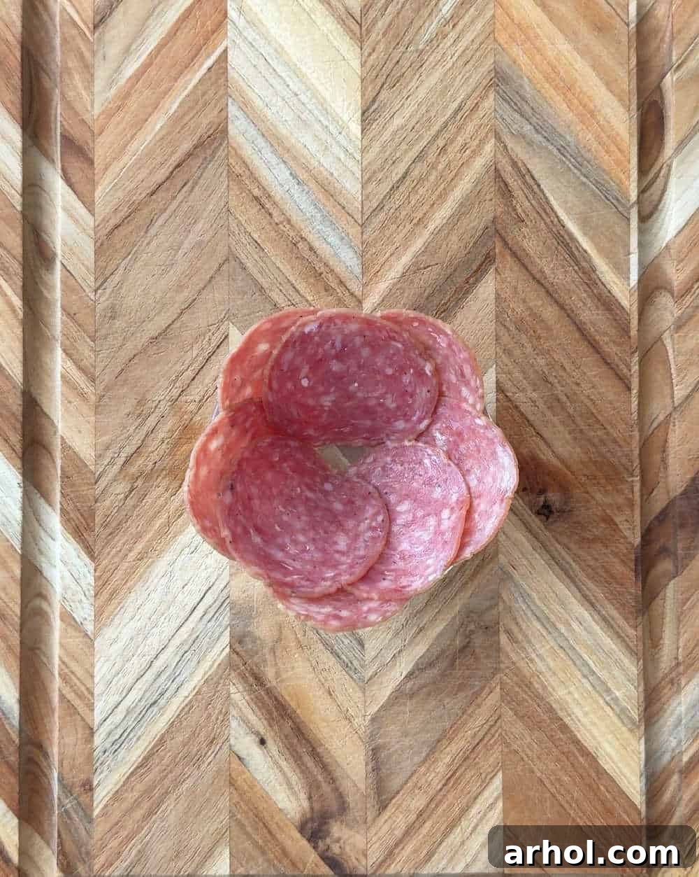 Step 6: Placing salami slices around the rim of a small glass, forming the outer petals of the rose.
