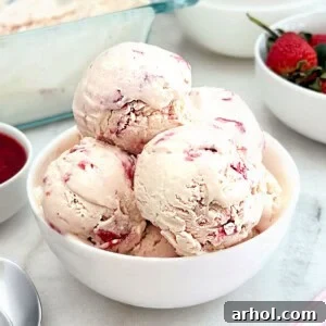 Bowl of homemade strawberry ice cream with fresh strawberries, a refreshing summer dessert.