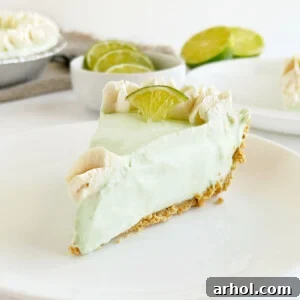 Slice of no-bake key lime pie with graham cracker crust on a plate.