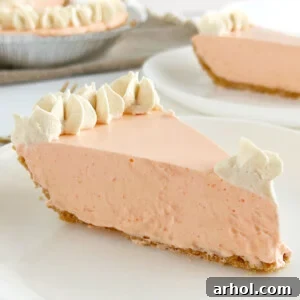 Slice of Jello orange creamsicle pie topped with whipped cream on a plate.