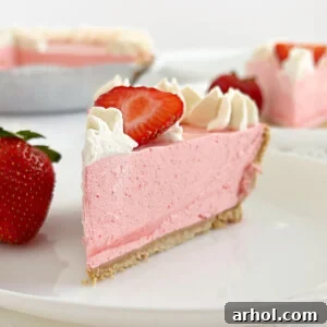 Slice of no-bake strawberry jello pie with Cool Whip, fresh strawberries, and whipped cream.