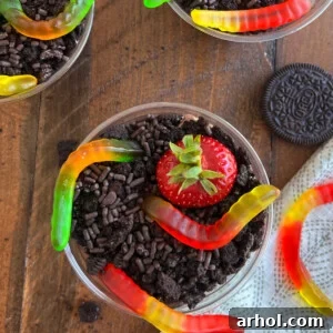 Dirt pie cups featuring gummy worms, Oreo cookies, and chocolate pudding.