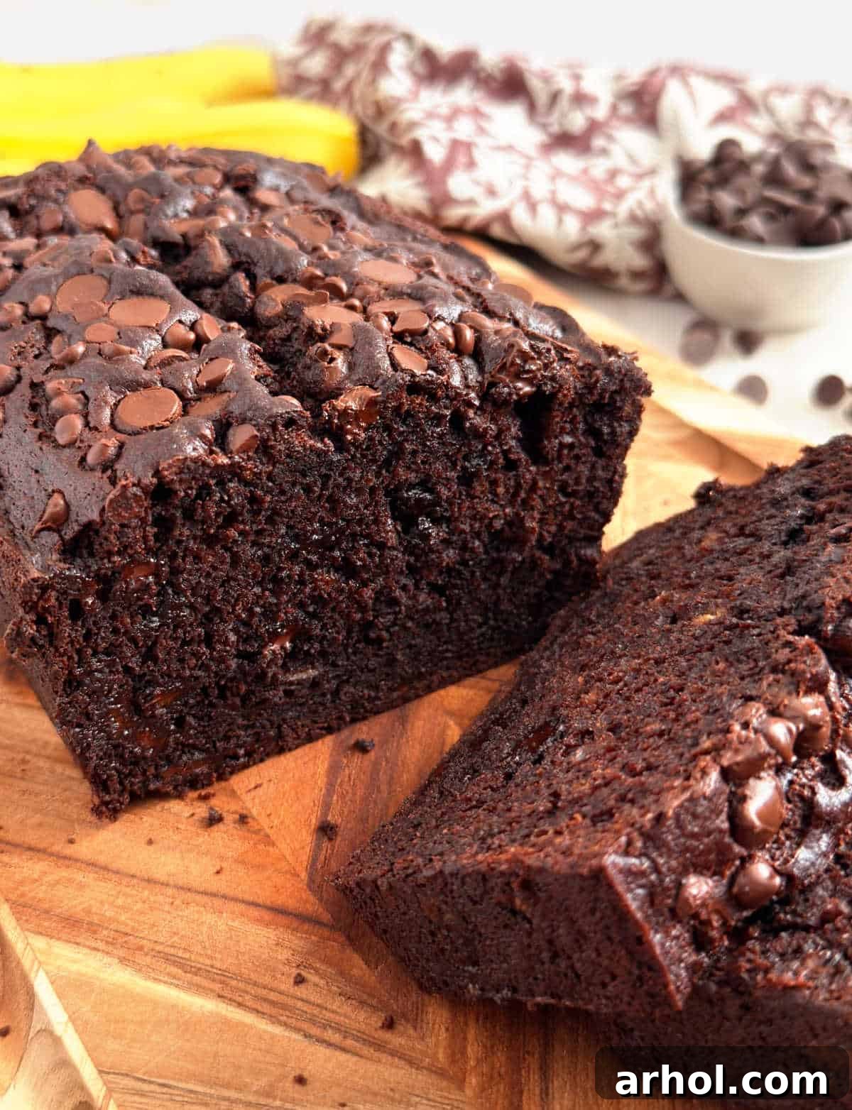 Slice of chocolate banana bread with chocolate chips on a cutting board, ready to be enjoyed.