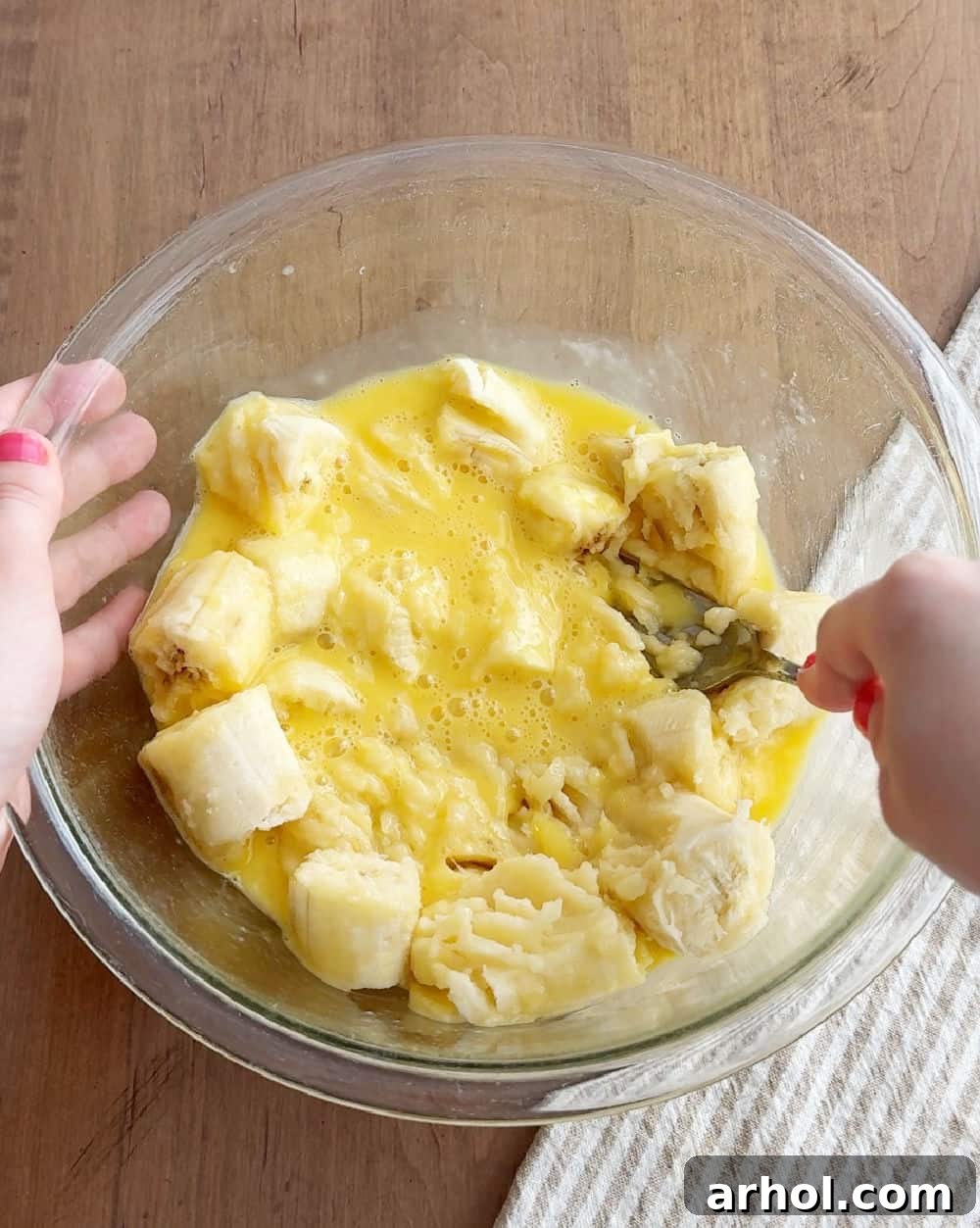 Mashing ripe bananas in a glass bowl, an essential first step for moist banana bread.