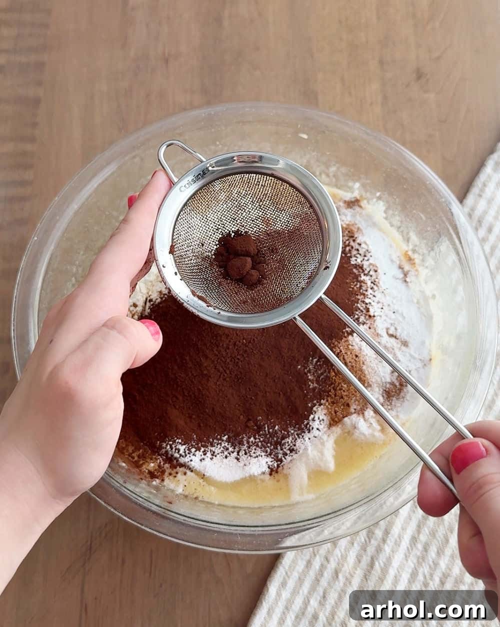 Sifting cocoa powder into the dry ingredients for a lump-free, rich chocolate banana bread.